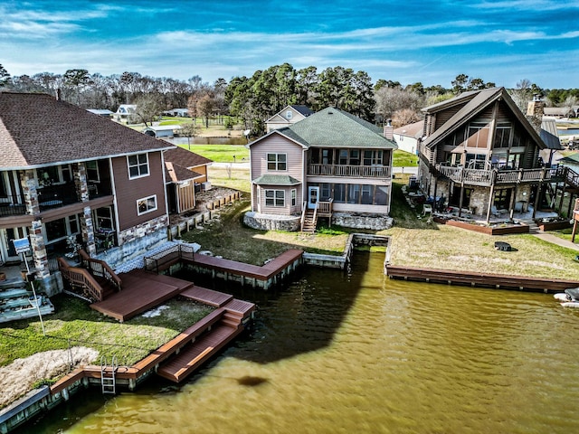 exterior space featuring a residential view, a sunroom, a deck with water view, and stairs