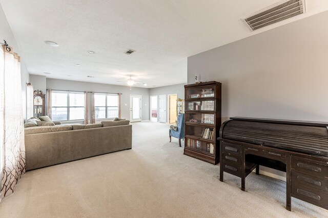 living area featuring light carpet, ceiling fan, and visible vents