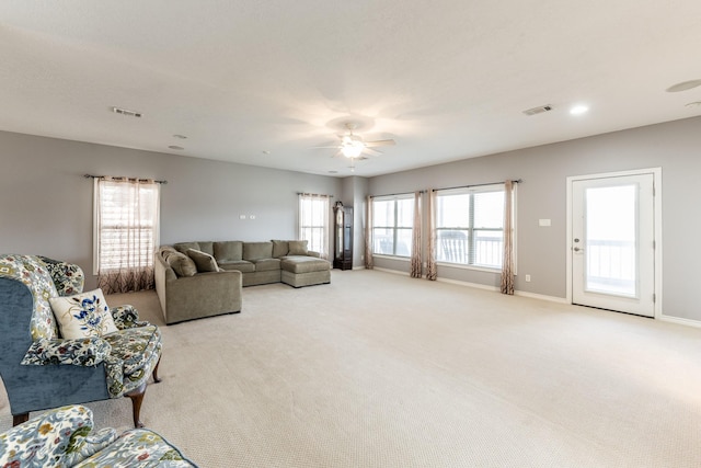 living area featuring a ceiling fan, light carpet, visible vents, and baseboards