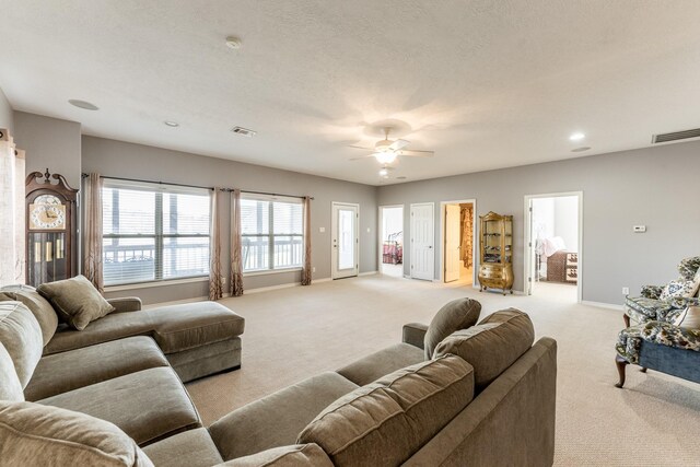 living room with light carpet, ceiling fan, visible vents, and baseboards