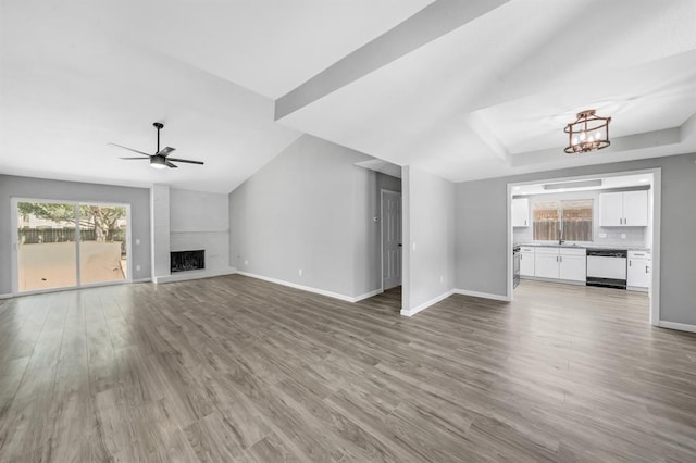 unfurnished living room with a healthy amount of sunlight, a large fireplace, baseboards, and wood finished floors