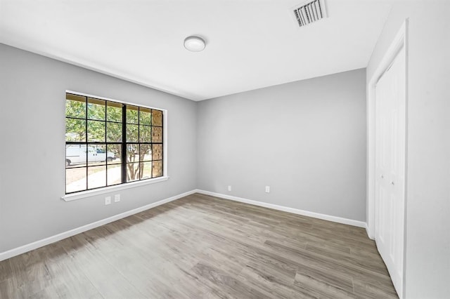 unfurnished bedroom featuring baseboards, a closet, visible vents, and wood finished floors