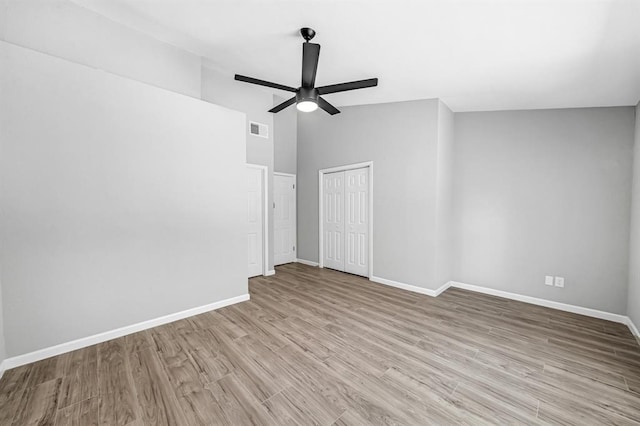 empty room featuring visible vents, baseboards, a ceiling fan, light wood-style flooring, and vaulted ceiling