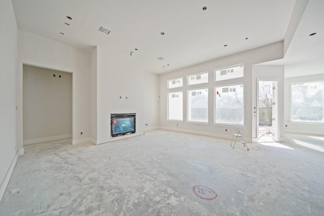 unfurnished living room with baseboards, visible vents, and a glass covered fireplace