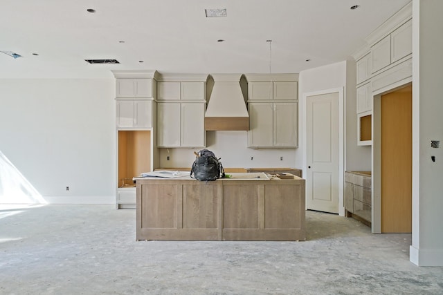 kitchen with premium range hood, baseboards, cream cabinetry, and a center island