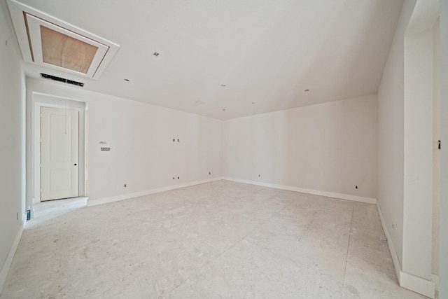 unfurnished room featuring visible vents, attic access, and baseboards