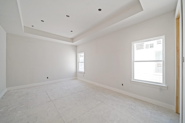 unfurnished room with a tray ceiling and baseboards