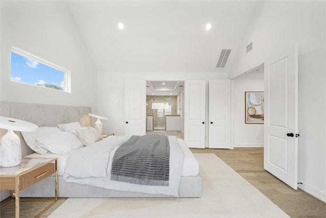 bedroom featuring recessed lighting, visible vents, light wood-style flooring, ensuite bathroom, and high vaulted ceiling