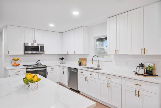 kitchen with decorative backsplash, white cabinetry, stainless steel appliances, and a sink