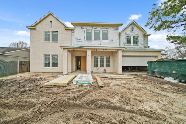 back of property with a garage, fence, and brick siding