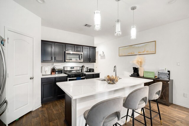 kitchen with dark wood-type flooring, visible vents, light countertops, appliances with stainless steel finishes, and hanging light fixtures