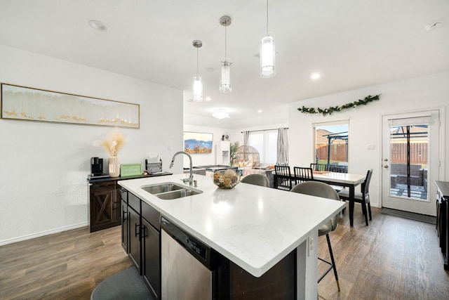 kitchen with a sink, light countertops, stainless steel dishwasher, a center island with sink, and pendant lighting