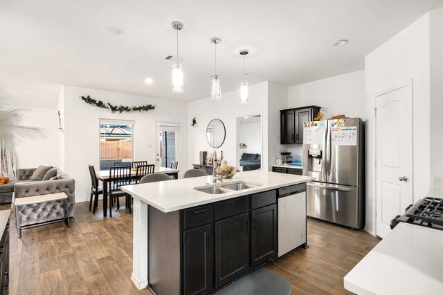 kitchen featuring a center island with sink, stainless steel appliances, light countertops, open floor plan, and a sink