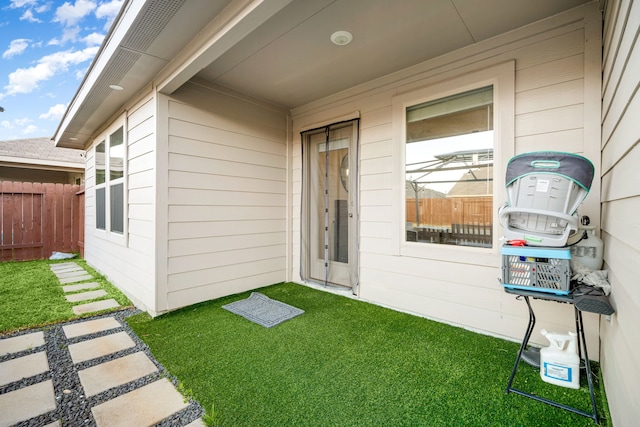 doorway to property with fence and a lawn