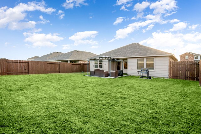 rear view of property featuring a yard, a fenced backyard, and a gazebo