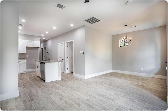 kitchen featuring visible vents, a kitchen island with sink, white cabinets, a sink, and dishwasher