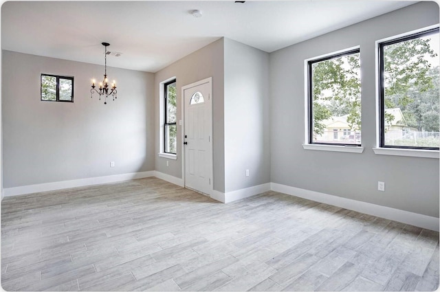 entryway with light wood-style floors, baseboards, and a chandelier