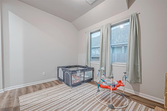 interior space featuring lofted ceiling, wood finished floors, and baseboards