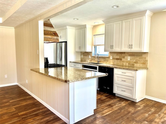 kitchen with black dishwasher, a sink, dark wood-style floors, and freestanding refrigerator