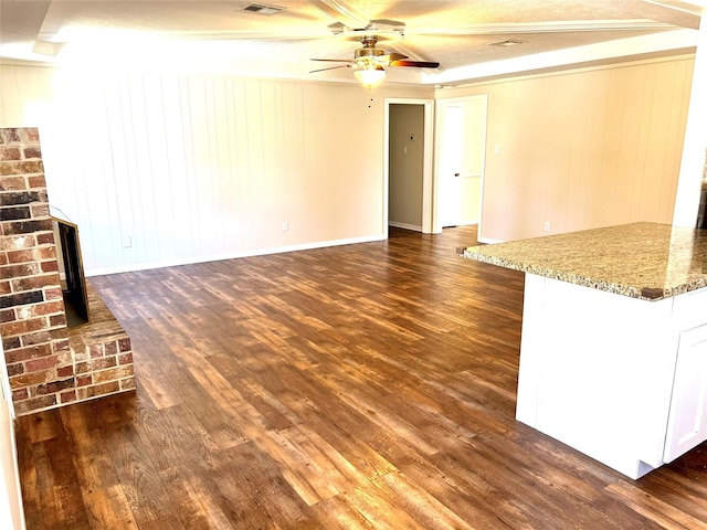 unfurnished living room featuring ceiling fan, dark wood finished floors, visible vents, and baseboards