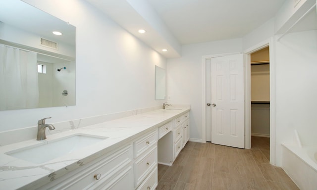 full bath featuring double vanity, visible vents, a sink, and wood finished floors