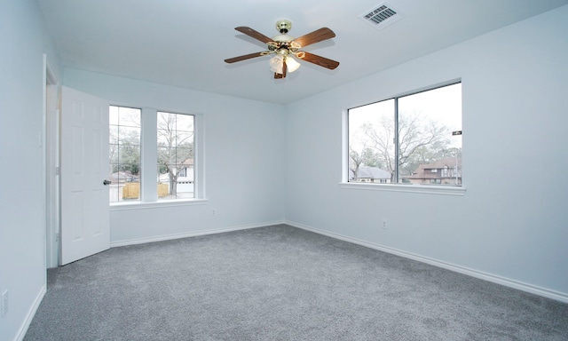 spare room with visible vents, dark carpet, baseboards, and ceiling fan