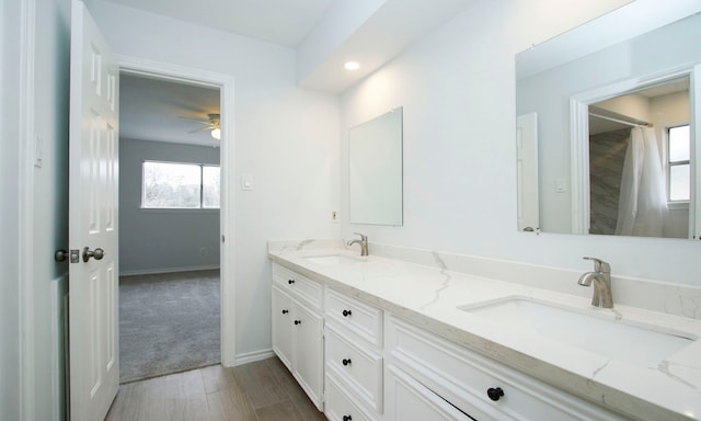 full bathroom featuring double vanity, baseboards, and a sink