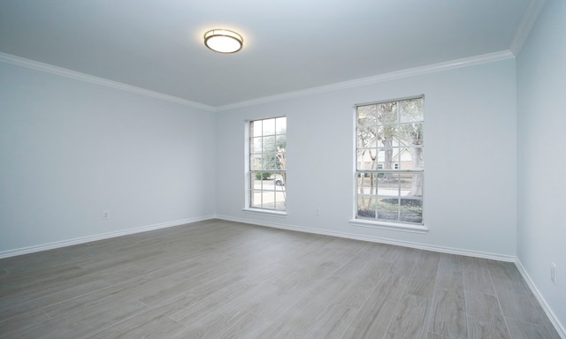 spare room featuring light wood-style floors, ornamental molding, and baseboards