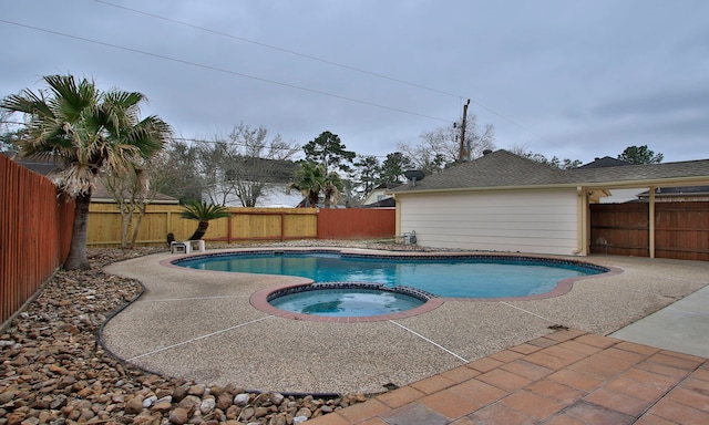 view of swimming pool with a pool with connected hot tub, a patio area, and a fenced backyard