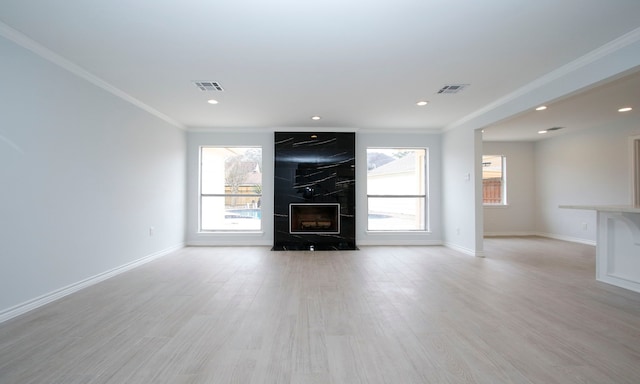 unfurnished living room featuring a large fireplace, visible vents, and a healthy amount of sunlight