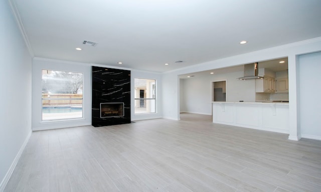 unfurnished living room featuring recessed lighting, a fireplace, visible vents, light wood finished floors, and crown molding