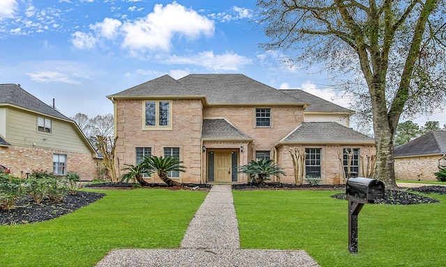 traditional home featuring brick siding, roof with shingles, and a front yard