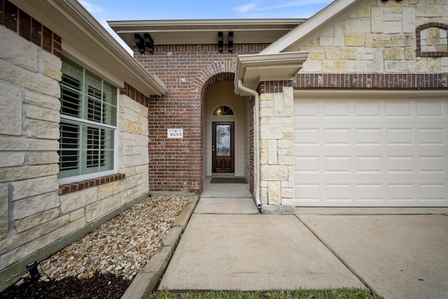 property entrance featuring a garage, stone siding, brick siding, and concrete driveway