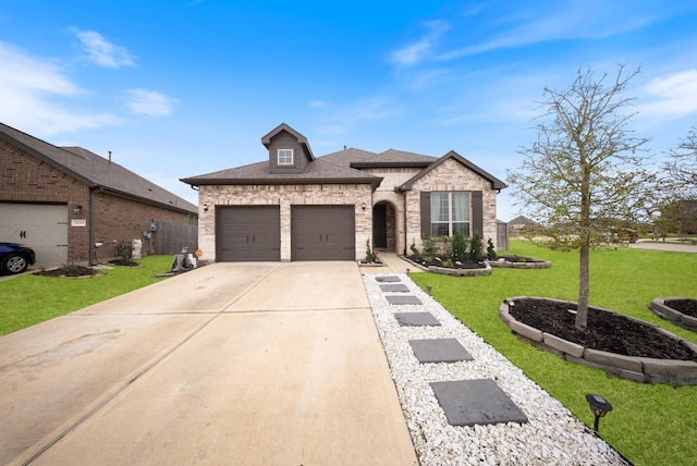 french provincial home featuring a garage, concrete driveway, roof with shingles, a front yard, and brick siding