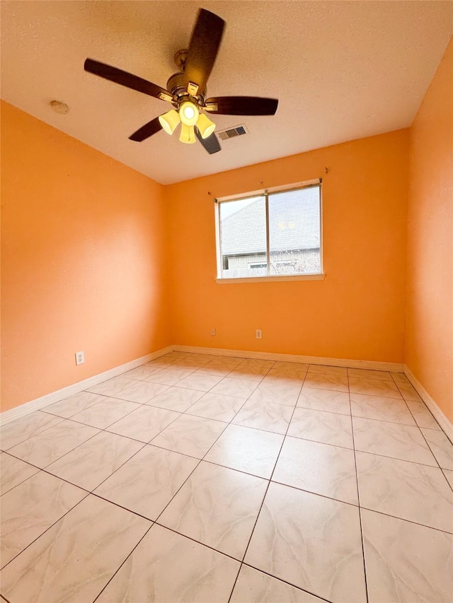 empty room with baseboards, a textured ceiling, visible vents, and a ceiling fan