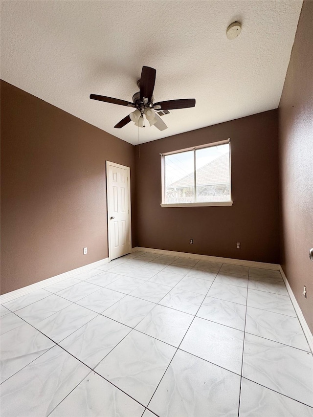 empty room featuring marble finish floor, a textured ceiling, baseboards, and a ceiling fan