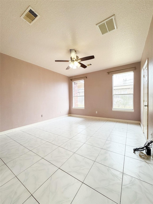 spare room with visible vents, ceiling fan, a textured ceiling, and baseboards