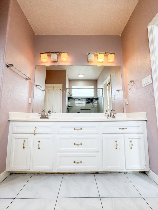 full bathroom with a stall shower, a textured ceiling, baseboards, and double vanity