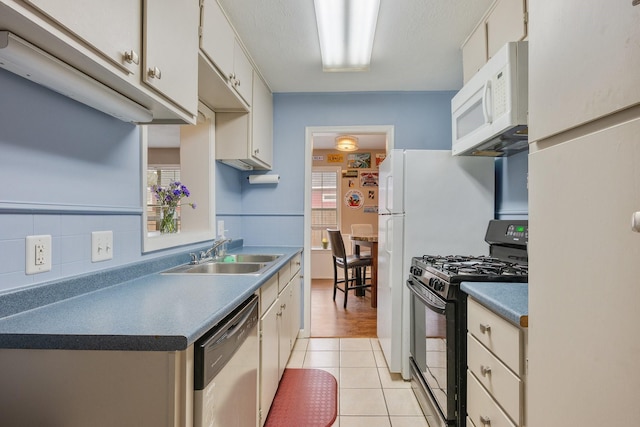 kitchen with white microwave, white cabinets, a sink, black range with gas cooktop, and dishwasher