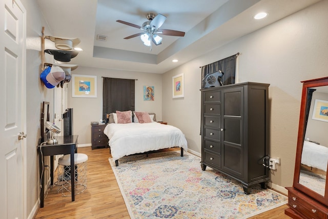 bedroom featuring a tray ceiling, recessed lighting, visible vents, wood finished floors, and baseboards