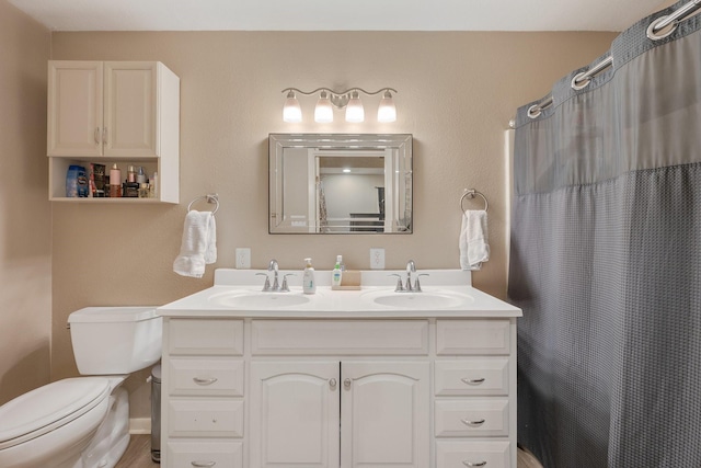 bathroom featuring a shower with shower curtain, a sink, toilet, and double vanity