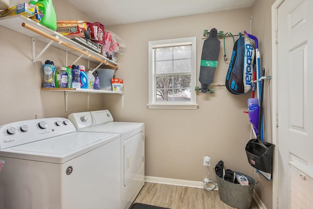 washroom with laundry area, baseboards, washer and clothes dryer, and light wood finished floors