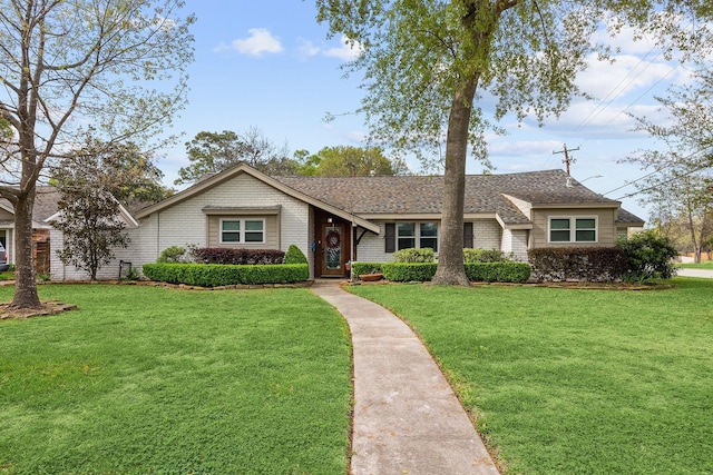 view of front of property featuring roof with shingles, brick siding, and a front lawn