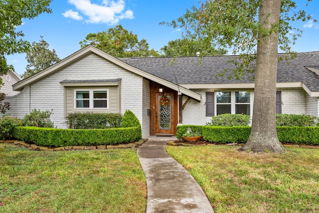 view of front of property featuring roof with shingles and a front yard