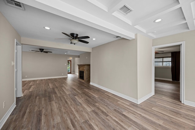 unfurnished living room with baseboards, visible vents, wood finished floors, and a glass covered fireplace