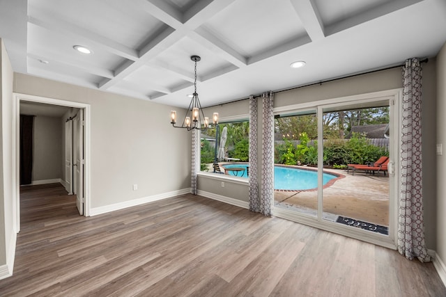 interior space featuring beam ceiling, a notable chandelier, wood finished floors, coffered ceiling, and baseboards