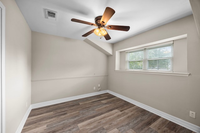 spare room featuring dark wood-type flooring, a ceiling fan, visible vents, and baseboards