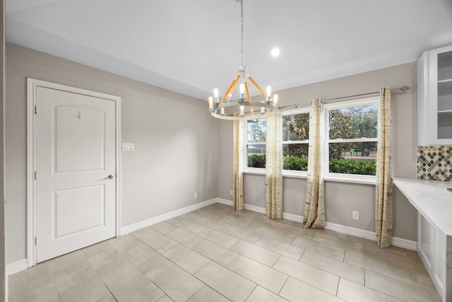 unfurnished dining area featuring an inviting chandelier, baseboards, vaulted ceiling, and light tile patterned flooring