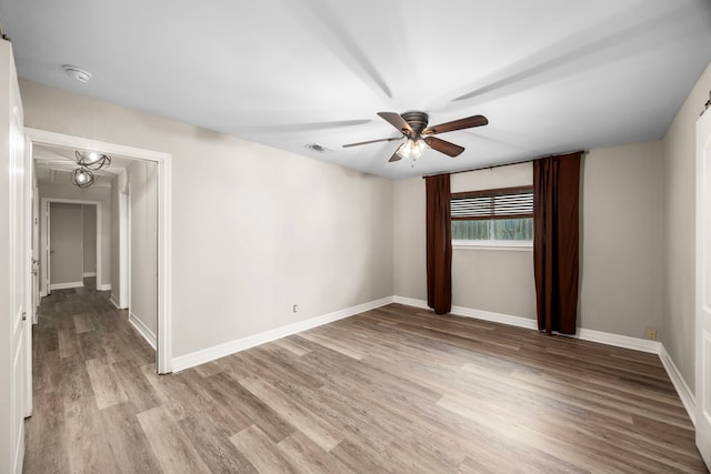 unfurnished room featuring a ceiling fan, light wood-type flooring, visible vents, and baseboards