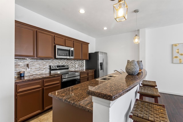 kitchen with a breakfast bar, decorative light fixtures, tasteful backsplash, appliances with stainless steel finishes, and a sink